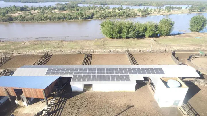 Galpão de manejo com painéis solares em frente à lagoa